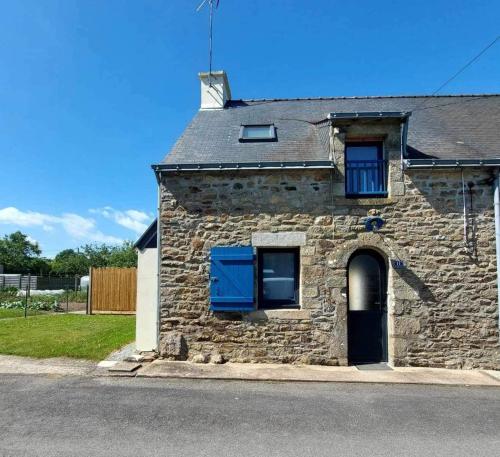 a stone house with blue doors on a street at Maison Bretonne avec piscine in Marzan