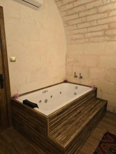 a bath tub in a room with a brick wall at ABGAR Otel in Sanlıurfa
