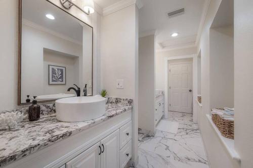 a white bathroom with a sink and a mirror at Just Wow! Luxury & Huge Heated Pool & Spa Home! in Clearwater