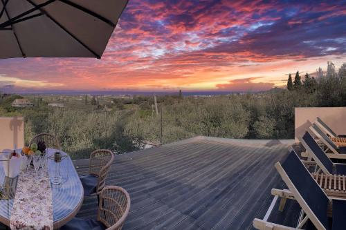 a table and chairs on a deck with a sunset at Villa de la Vita in Katastárion