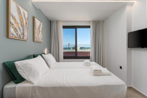 a bedroom with a large white bed with a window at Plakias Seaside Residences - Dandelion in Plakias