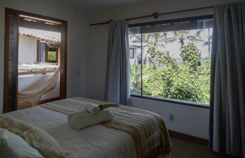 a bedroom with a bed and a large window at Pousada Vila do Mar in Caraíva