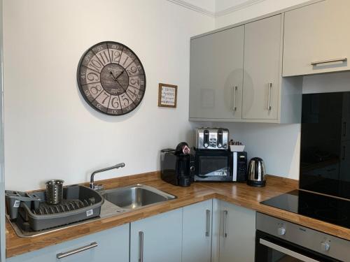 a kitchen with a sink and a clock on the wall at Market Place Serviced Apartments, Leek in Leek