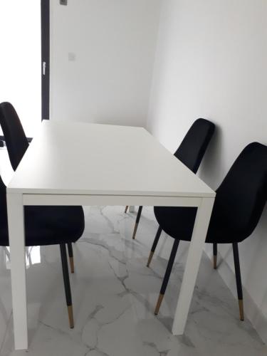 une table à manger blanche avec quatre chaises noires dans l'établissement Ali, à Savigny-le-Temple