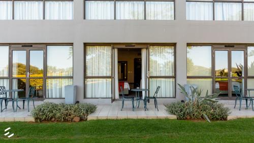 a building with chairs and tables and windows at Phakalane Golf Estate Hotel & Convention Centre in Gaborone
