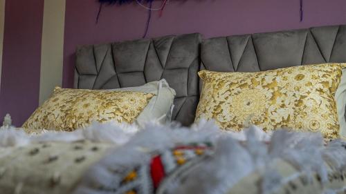 a bed with a gray headboard and pillows at Gîte Forest Tagroumte in Azrou