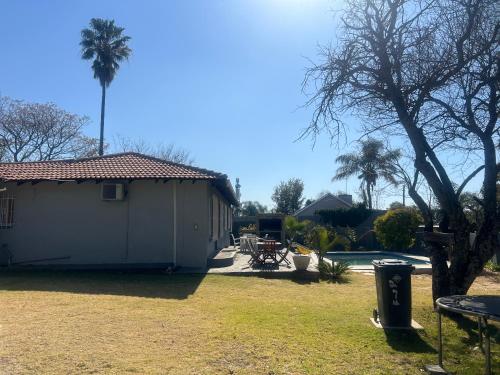a small white building with a picnic table and palm trees at Vic's place - With backup power in Sandton