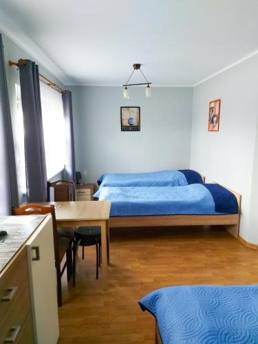 a bedroom with a bed and a table and a dining room at Pensjonat Bryza in Karwia