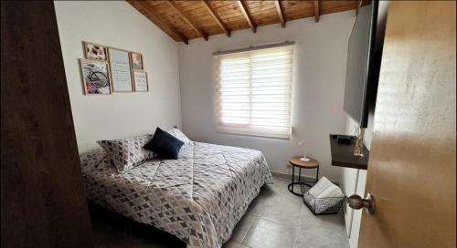 a small bedroom with a bed and a window at Cabaña Linda y acogedora in Guarne