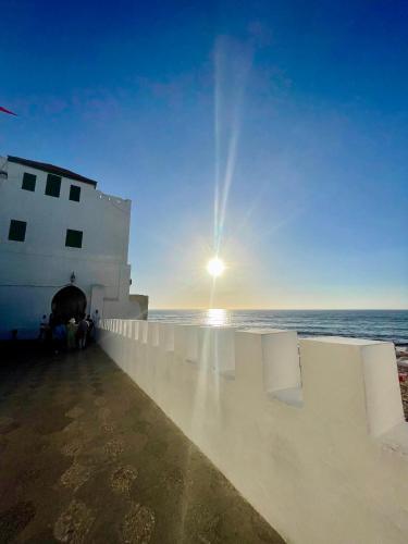 a view of the ocean with the sun setting behind a building at Casa bleuté in Asilah
