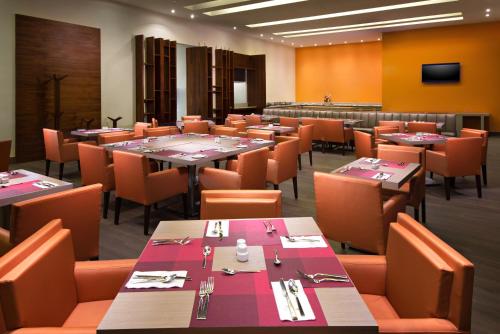 a dining room with tables and chairs and a television at Hilton Garden Inn Monterrey Airport in Monterrey