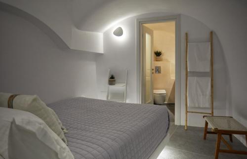 a white bedroom with a bed and a bathroom at 1949 Cave Residence in Pirgos