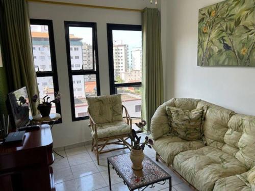 - un salon avec un canapé, une chaise et des fenêtres dans l'établissement Lindo Apto 502 em PG Ocian, à Praia Grande