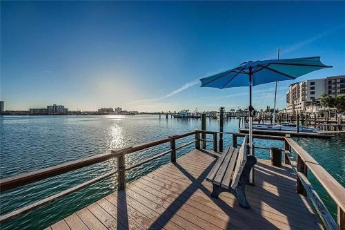a wooden pier with a bench and an umbrella at The Seashell Suite with Private Balcony and Walk to Beach in Clearwater Beach