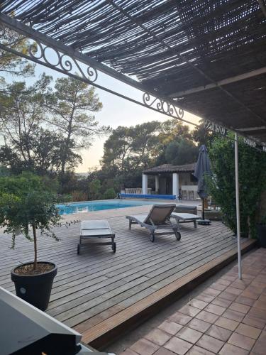 a patio with a table and a bench and a pool at Villa Sisyphe chambre"la jeanette" in Le Thoronet