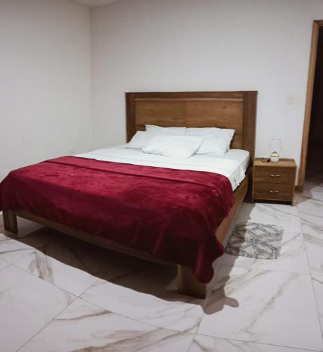 a bedroom with a bed with a red blanket on it at CASA LA ESTANCIa in Tena
