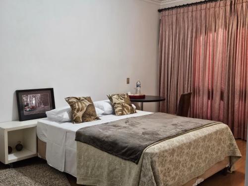 a bedroom with a bed and a table with a television at Charmosa e ampla suíte in Sao Paulo