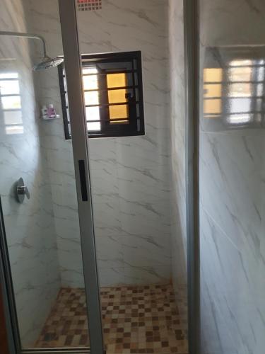 a shower with a glass door in a bathroom at Modern and cozy apartment in Lusaka