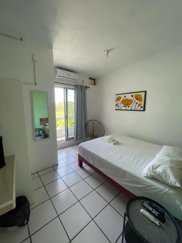 a bedroom with a bed and a table and a window at Hotel Oasis Cuyutlan in Cuyutlán