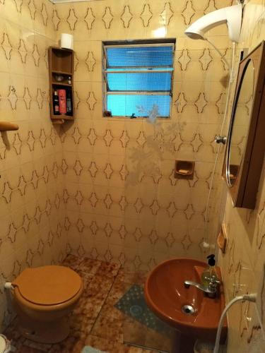 a bathroom with a toilet and a sink and a window at Casa Klos - Quartos amplos in Curitiba