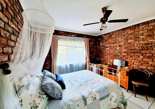 a bedroom with a bed and a brick wall at Boknesstrand Self-catering Accommodation Holiday Home - a Mermaids Cottage minutes to the beach, lagoon, shops & more! in Boknes