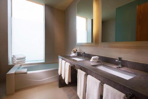 a bathroom with two sinks and a tub with towels at Hilton Garden Inn Monterrey Airport in Monterrey