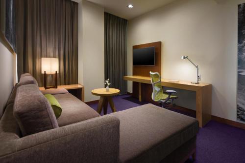a hotel room with a couch and a desk at Hilton Garden Inn Monterrey Airport in Monterrey