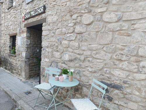 a table and chairs in front of a stone wall at Casa MELCHOR in Villanúa