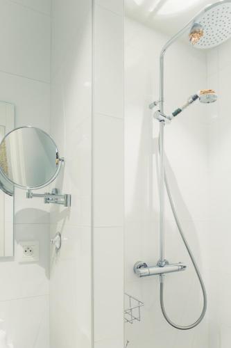 La salle de bains blanche est pourvue d'une douche et d'un miroir. dans l'établissement La Cabane du Pont de l'Ignon, à Frénois