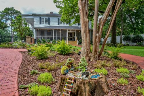 a garden with a toy figure sitting on a tree stump at Bama Bed and Breakfast - Tusk Suite in Tuscaloosa
