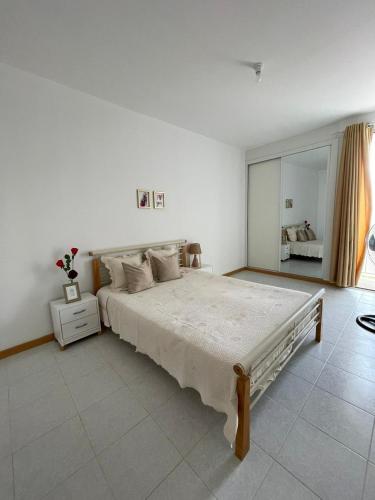 a white bedroom with a large bed and a window at Casa do Encanto in Praia