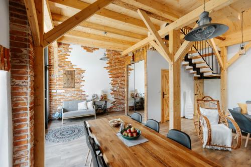 a living room with a wooden table and a brick wall at JÓZEFÓWKA Stara Stodoła in Zagórze