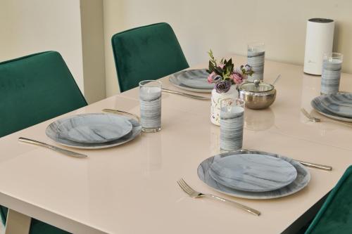 a table with plates and utensils on it at Five Business-class rooms in R-house near Mega Center Almaty in Almaty