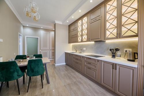 a kitchen with wooden cabinets and a table with green chairs at Five Business-class rooms in R-house near Mega Center Almaty in Almaty