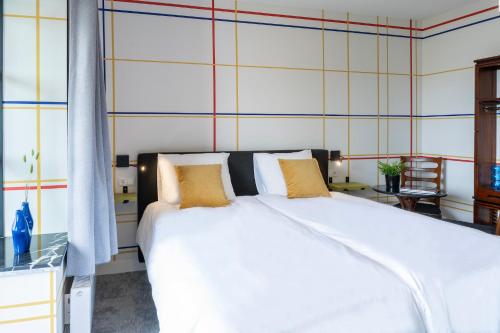 a bedroom with a large white bed with yellow pillows at Modern Hotel Central Tilburg, Balcony & Kitchen in Tilburg