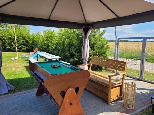 a ping pong table and a bench under an umbrella at Perła Bałtyku Jarosławiec in Jezierzany