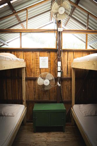 a room with two bunk beds and a fan at Flutterby House Hostel in Uvita