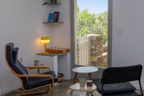 a room with two chairs and a table and a window at By The Stone Tinos in Triandáros