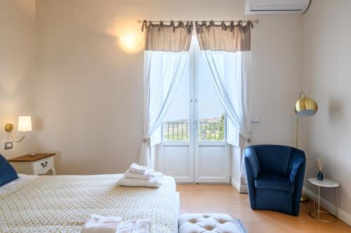 a bedroom with a bed and a blue chair and a window at Palazzo Gargano in Prignano Cilento