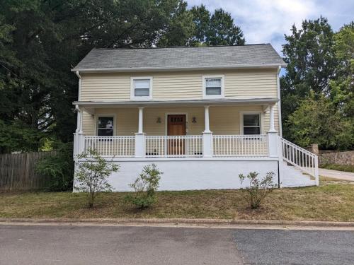 a yellow house with a white porch and a white porch at Modern Mill House Walk to Downtown Durham in Durham