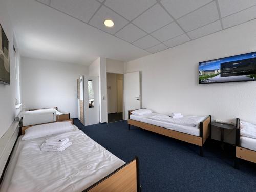 a room with two beds and a tv on the wall at Thuja Apartments Karlsruhe-Neureut by KurzZeit in Karlsruhe