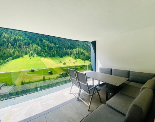a dining room with a large window overlooking a golf course at Hollywood Dream Penthouse & Apartments mit privater Sauna nahe Ischgl in Kappl