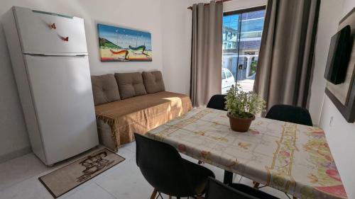 a kitchen with a table and a refrigerator and a couch at RESIDENCIAL PORTAL DO SOL in Bombinhas