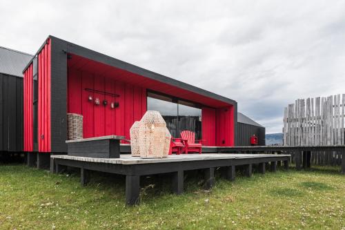a red and black building with a bench and chairs at Kau Rio Serrano in Torres del Paine