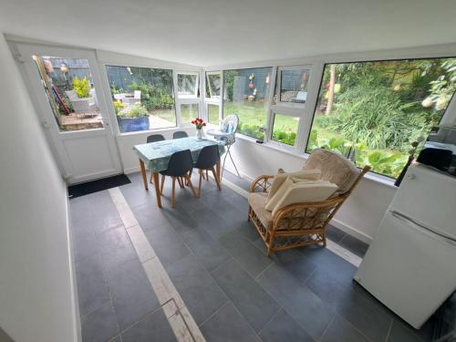 Un comedor con mesa y sillas y ventanas. en Willow Bungalow Quiet and secluded, en Carbis Bay