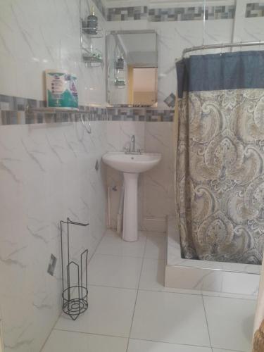 a white bathroom with a sink and a shower at Bobby Vacational Home in Portmore