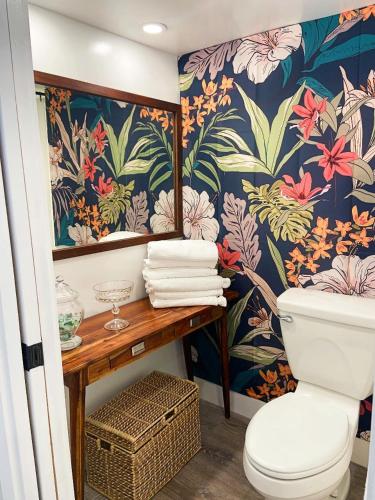 a bathroom with a toilet and a flower wallpaper at Luxury Beachfront Condo in Hauula