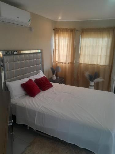 a bedroom with a white bed with two red pillows at Bobby Vacational home in Portmore