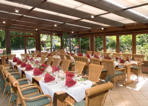 un comedor con mesas y sillas con almohadas rojas en Hotel Ferien auf der Heid en Eversen