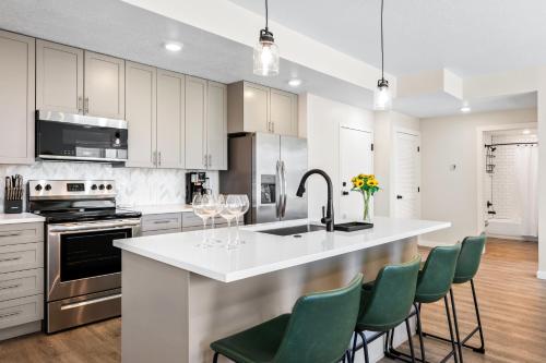 een keuken met witte kasten en een keukeneiland met groene stoelen bij Lagoon Desert Retreat condo in St. George